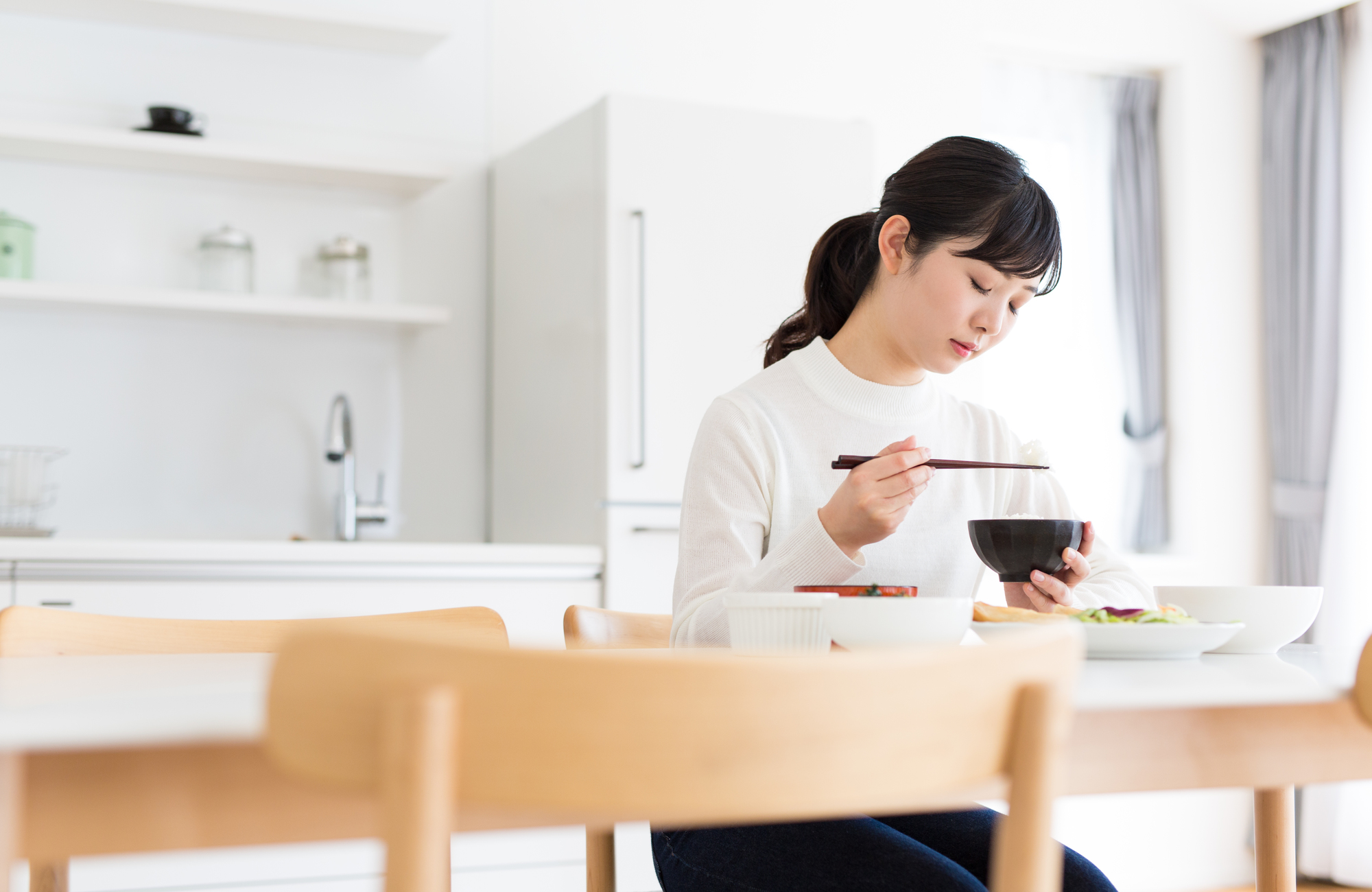 食事をとりながらスマートフォンを見る女性